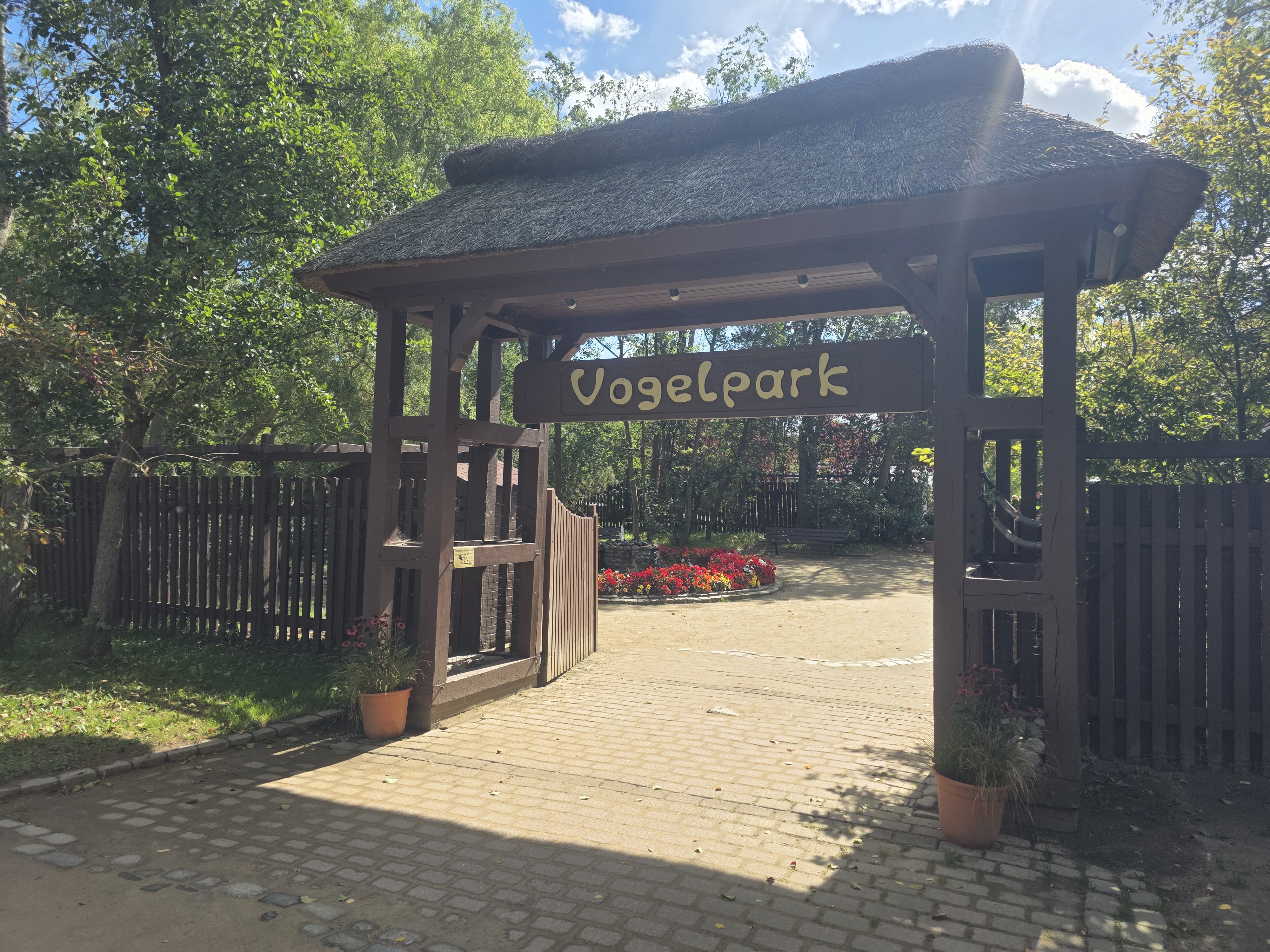 Das Eingangsportal vom Vogelpark Niendorf, ein reetgedeckter Torbogen aus Holz.